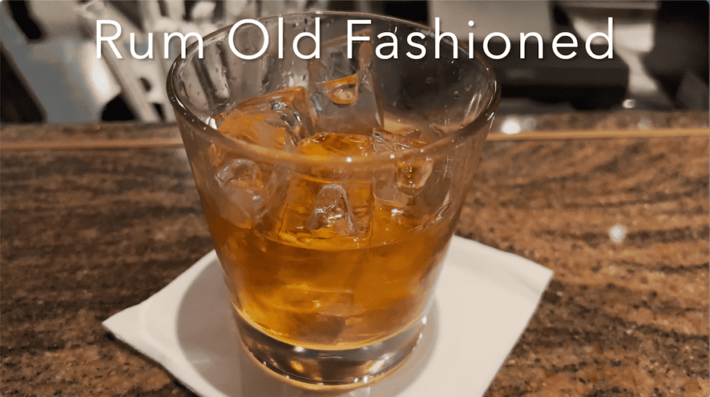 caramel colored liquid with ice cubes in glass tumblers on top of white napkin on granite counter